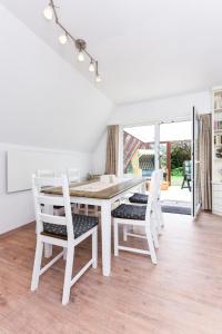 ein weißes Esszimmer mit einem weißen Tisch und Stühlen in der Unterkunft Ferienhaus Windspiel in Neuharlingersiel