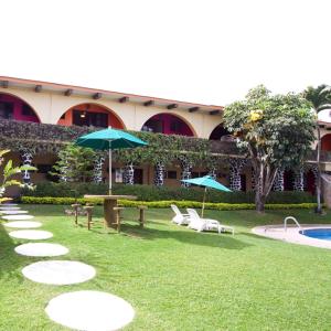 einen Garten mit Stühlen und Sonnenschirmen sowie einem Pool in der Unterkunft Hotel & Motel Hacienda Jiutepec in Jiutepec