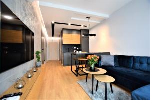 Premium Apartments Rzeszów في جيشوف: غرفة معيشة مع أريكة وطاولات ومطبخ