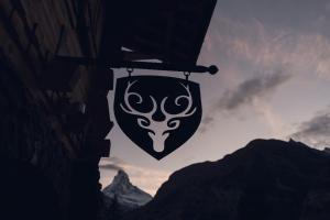 ein Schild mit einem Hirsch, der von einem Gebäude hängt. in der Unterkunft Nomad by CERVO Mountain Resort in Zermatt