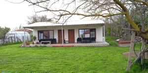 une petite maison dans une cour avec une pelouse verte dans l'établissement Draganov House, à Durankulak