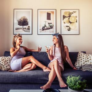 Dos mujeres sentadas en un sofá con copas de vino en Smart & Green Living by Ambiente, en Bratislava