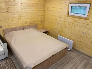 a small bedroom with a bed in a wooden room at Touristic complex Taiezhnik in Manzherok