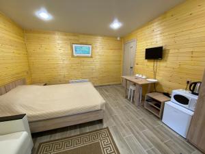 a bedroom with a bed and a table and a tv at Touristic complex Taiezhnik in Manzherok