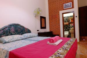 a bedroom with a bed with a pink blanket at Kampoeng Djawa Hotel in Yogyakarta