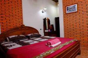 a bedroom with a wooden bed with a brick wall at Kampoeng Djawa Hotel in Yogyakarta