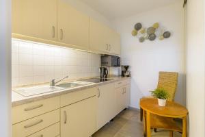 uma cozinha com armários brancos, um lavatório e uma mesa em Welle und Woge em Dagebüll