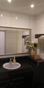 um lavatório de casa de banho com um espelho e um vaso de flores em Apartment Hotel City Inn em Colónia