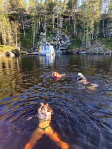 a couple of people swimming in a lake at Peace & Quiet Hotel in Jokkmokk