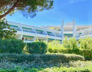 a white building with a garden in front of it at L'HERMITAGE - Studio moderne - Piscine - Ascenseur - Quart Golf in La Grande-Motte