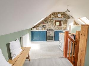 a kitchen with blue cabinets and a stone wall at Brithgwm Canol in Dolgellau