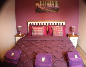a bedroom with a large bed with purple sheets and purple pillows at Immaculate 1 Bed Apartment in Pitlochry Scotland in Pitlochry