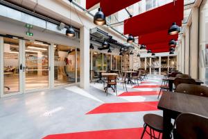 波尔多MEININGER Hotel Bordeaux Gare Saint-Jean的一间红色地毯上带桌椅的餐厅