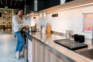 a woman standing at a counter preparing food at MEININGER Hotel Bordeaux Gare Saint-Jean in Bordeaux