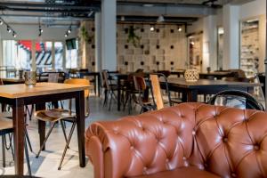 a leather couch in a restaurant with tables and chairs at MEININGER Hotel Bordeaux Gare Saint-Jean in Bordeaux