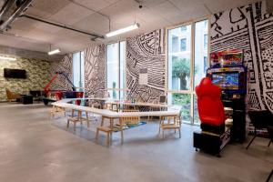 a room with a table and chairs and a video game at MEININGER Hotel Bordeaux Gare Saint-Jean in Bordeaux