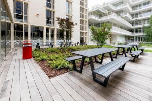 a group of picnic tables outside of a building at MEININGER Hotel Bordeaux Gare Saint-Jean in Bordeaux