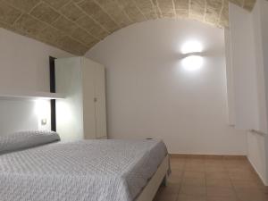 ein Schlafzimmer mit einem weißen Bett und einer weißen Wand in der Unterkunft Ugento Dimora in Ugento