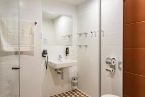 a bathroom with a shower, sink, and toilet at MEININGER Hotel Zürich Greencity in Zurich