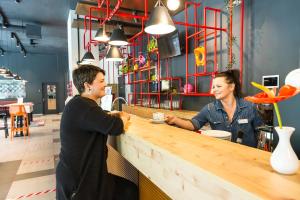 Un uomo e una donna seduti al bar di MEININGER Hotel Zürich Greencity a Zurigo