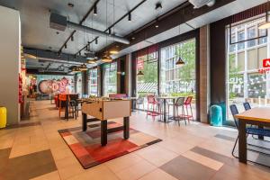 a restaurant with tables and chairs and windows at MEININGER Hotel Zürich Greencity in Zurich