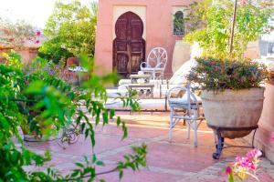 eine Terrasse mit Stühlen und Blumen vor einem Haus in der Unterkunft DAR CHIBANIA in Marrakesch