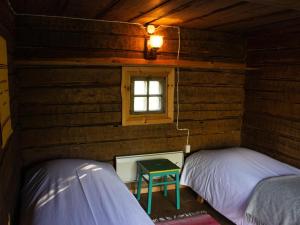 two beds in a log cabin with a window at Tarina-Aho in Vuonislahti