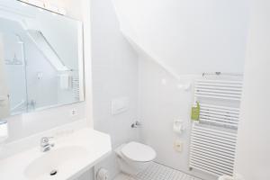 biała łazienka z umywalką i toaletą w obiekcie Stadthotel Engel w mieście Ettlingen