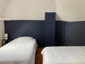 a bedroom with two beds and a blue accent wall at L'Aube en Somme in Millencourt-en-Ponthieu