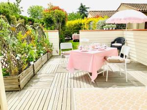 einen rosa Tisch mit Stühlen und einem Sonnenschirm auf einer Terrasse in der Unterkunft Cottage Blagnac in Beauzelle