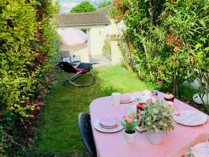 una mesa rosa con platos y flores. en Cottage Blagnac, en Beauzelle