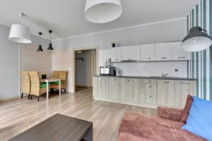 a kitchen and living room with a couch and a table at Grand Apartments Szafarnia 8 in Gdańsk