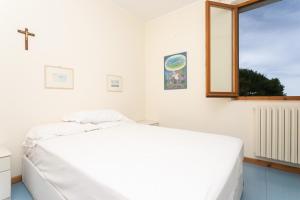 ein weißes Schlafzimmer mit einem Bett und einem Fenster in der Unterkunft M134 -Marcelli, quadrilocale con terrazzo a 50mt dal mare in Marcelli