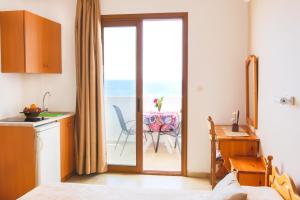 a room with a kitchen and a balcony with a table at Hotel Krinos in Karpathos