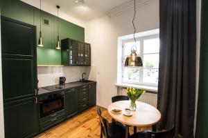a kitchen with green cabinets and a wooden table at Apartamenty FRETA4 Warsaw Old Town Apartments Warszawa Stare Miasto in Warsaw