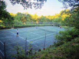 two people playing tennis on a tennis court at Le Jas des Cannebieres in Villeneuve
