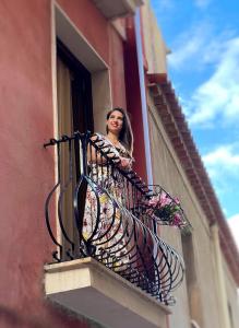una donna che guarda fuori da un balcone con fiori di Domus Cuseni a Taormina