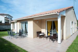 una casa y un patio con sillas y mesas. en Villa avec Jardin 600m² Netflix proche Toulouse, en Colomiers