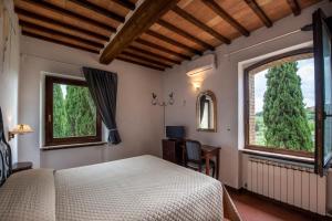 a bedroom with a bed and two windows at Hotel Vecchia Oliviera in Montalcino