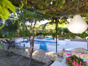 uma piscina com mesa e cadeiras e uma árvore em Loggos Summer House em Vasilikos