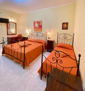 サン・ヴィート・ロ・カーポにあるBaglio Cusenza Roomsのベッドルーム1室(オレンジのシーツを使用したベッド2台付)