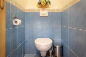 a blue tiled bathroom with a toilet and a basket of flowers at Apartman SIESTA*** in Liptovský Mikuláš