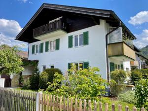 uma casa branca com persianas verdes e uma cerca em BÄRENALP Ferienwohnen em Garmisch-Partenkirchen