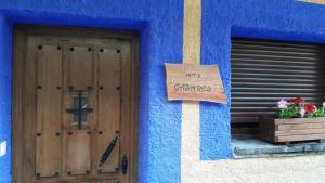 un bâtiment bleu avec un panneau à côté d'une porte dans l'établissement Alojamientos Rurales Hurdes Altas - La Antigua Guarderia, à Casares de las Hurdes