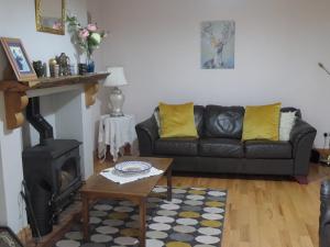 a living room with a black couch and a fireplace at Glebe cottage in Kinvara