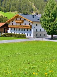 ein großes weißes Gebäude mit einem grünen Feld davor in der Unterkunft APART Kirschner in Sankt Leonhard im Pitztal