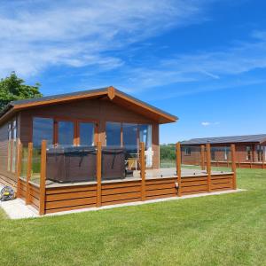 ein großes Haus mit einer großen Terrasse mit einem großen in der Unterkunft Luxury family Beechwood lodge with hot tub in Lochwinnoch