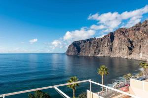 a view of the ocean with palm trees and cliffs at Los Gigantes Paradise in Acantilado de los Gigantes