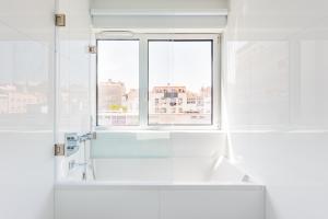 uma casa de banho branca com uma janela e uma banheira em Estrela Modern Flat @ Infante Santo em Lisboa