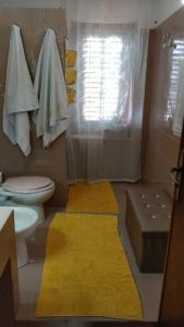 La salle de bains est pourvue de toilettes et d'un tapis jaune. dans l'établissement la finestra sul mare piano 2, à Trappeto